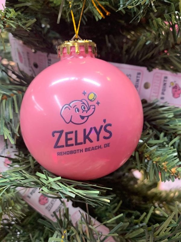 A pink ornament is hanging on the christmas tree.