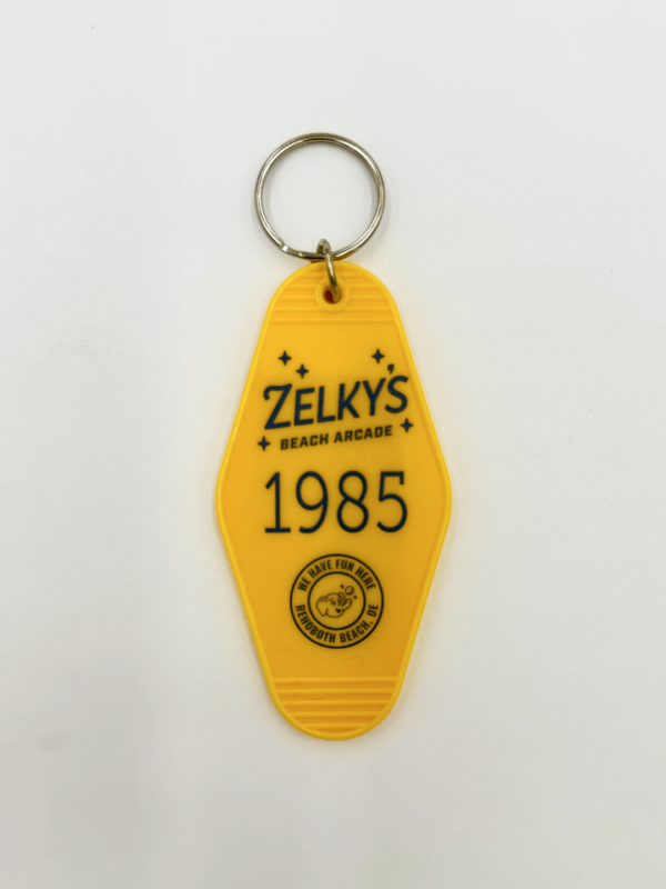 A yellow key chain with the name of zelky 's beach house and date 1 9 8 5.