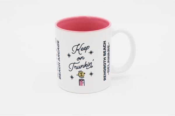 A white mug with pink inside and the words " keep on trunkin ".